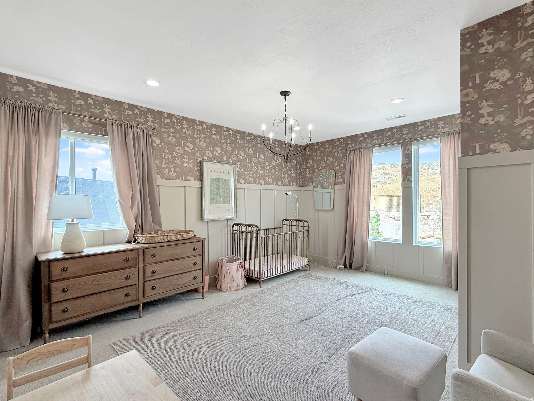 Room featuring board and batten wall paneling, patterned wallpaper, multiple windows, and a chandelier