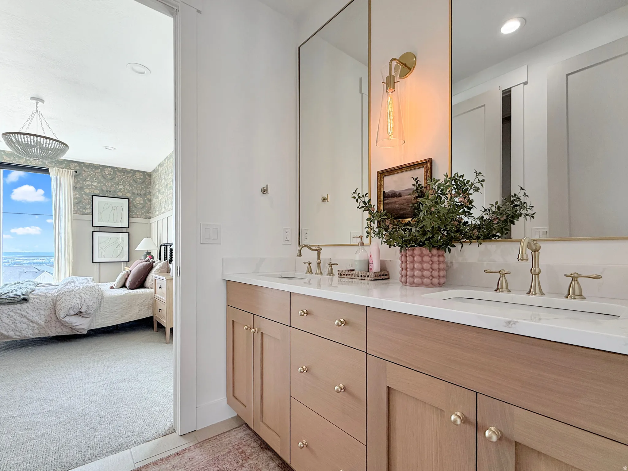 Dual vanity with light wood-finish cabinetry, gold-toned hardware, and rectangular undermount sinks