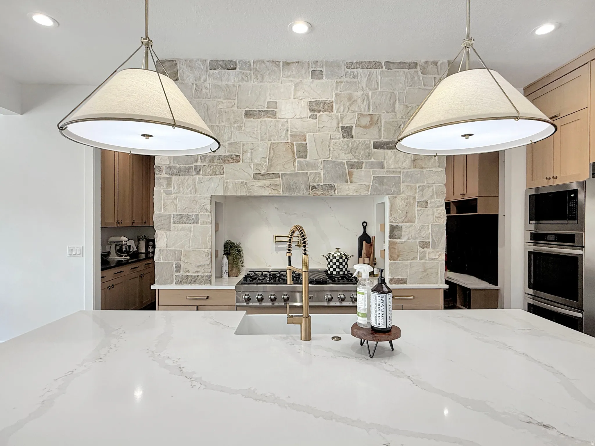 Kitchen island featuring a white countertop with integrated sink and brass-finish faucet