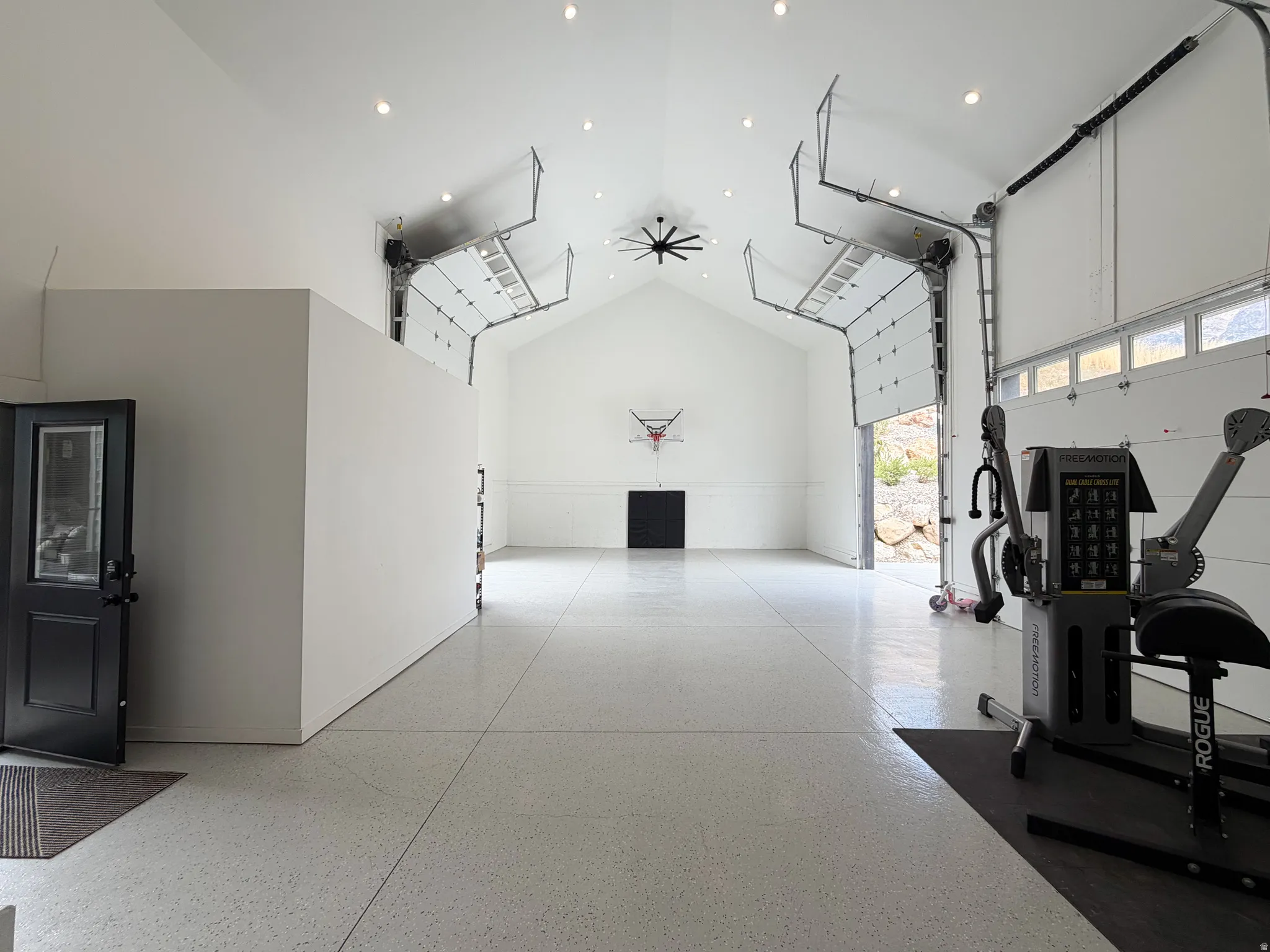 Vaulted ceiling, recessed lighting, industrial-style garage doors, epoxy flooring, interior partition wall
