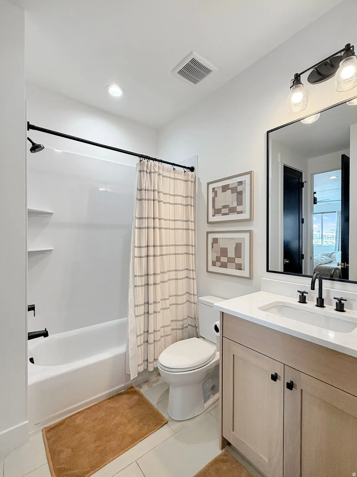 Bathroom featuring a single vanity with light-toned cabinetry, a white countertop, and a black faucet