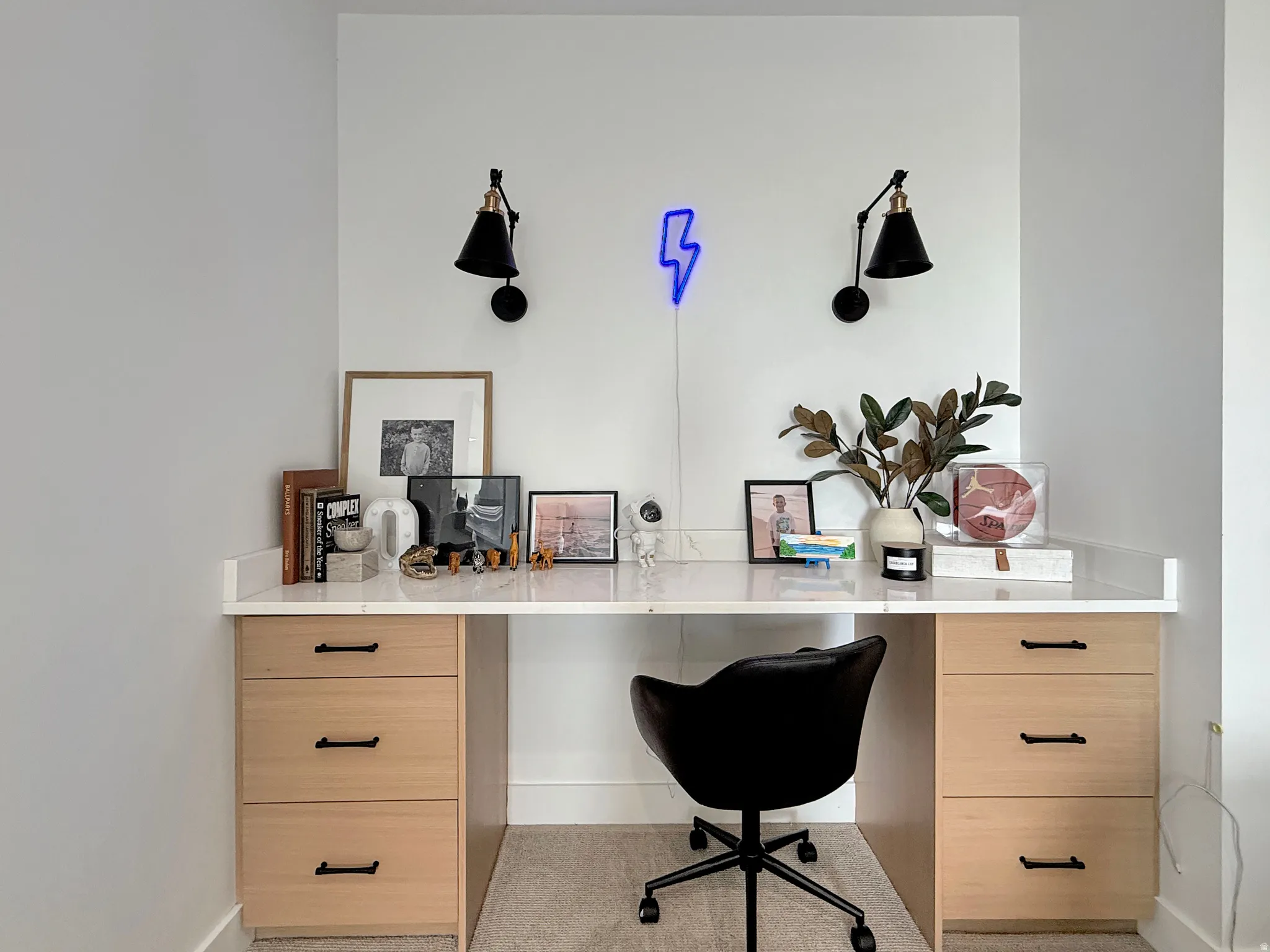Built-in desk featuring a light wood-finish cabinetry, a white countertop, and wall-mounted sconces