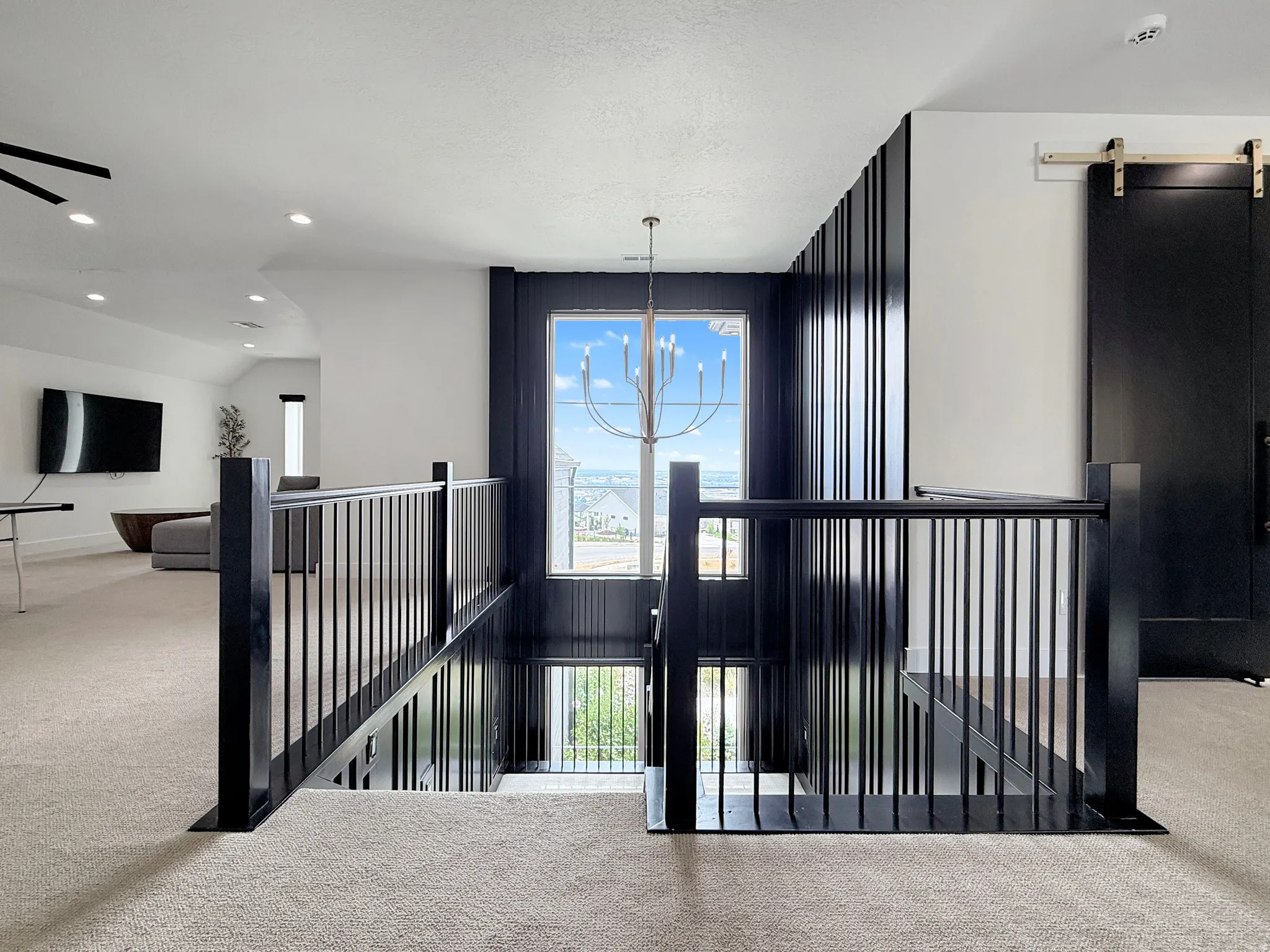 Open loft area with recessed lighting, a prominent chandelier, and a black barn door