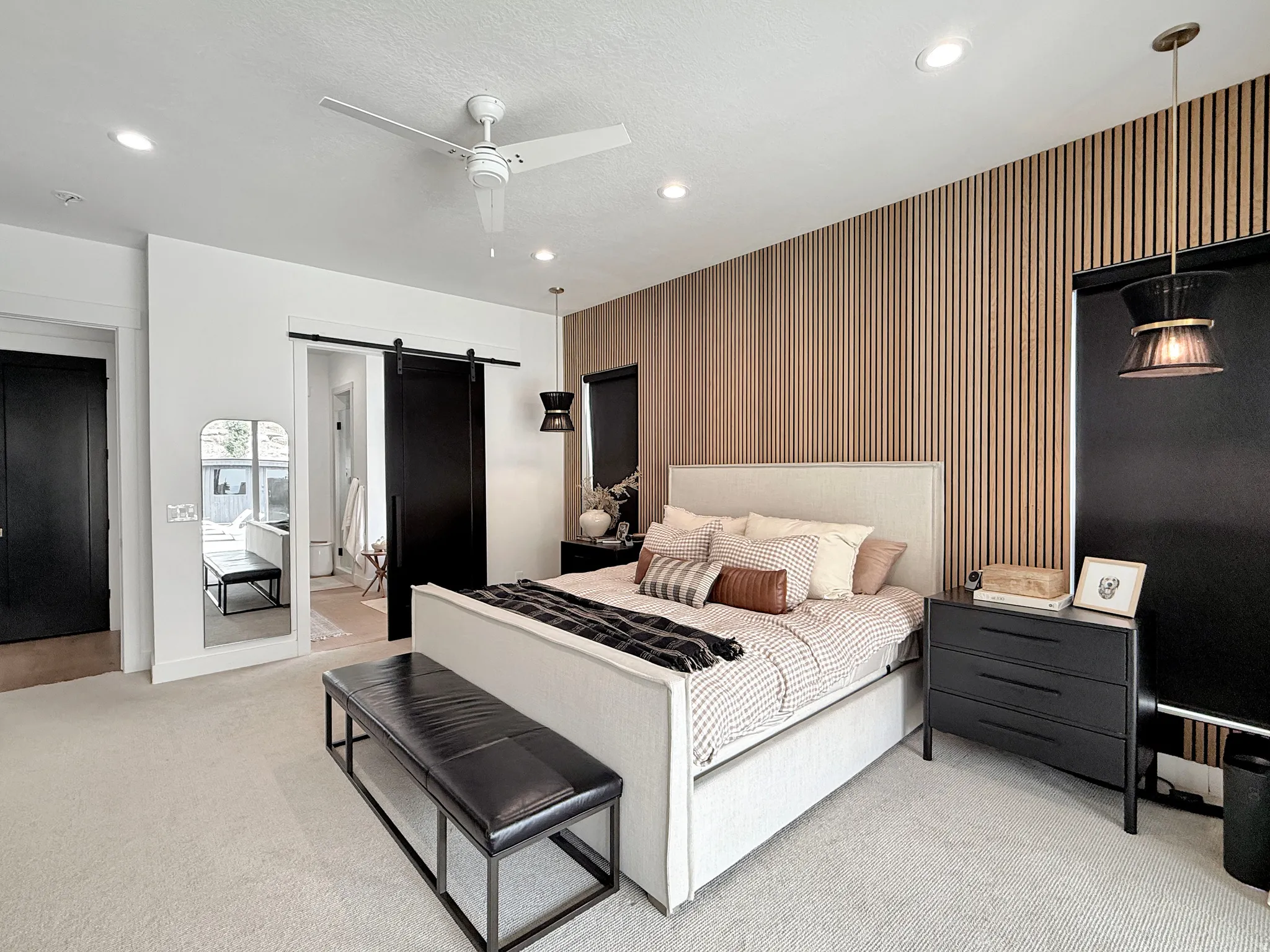 Wall-mounted wood paneling detail, recessed ceiling lights, ceiling fan, dark-finish barn door, and a dark-finish single-panel door