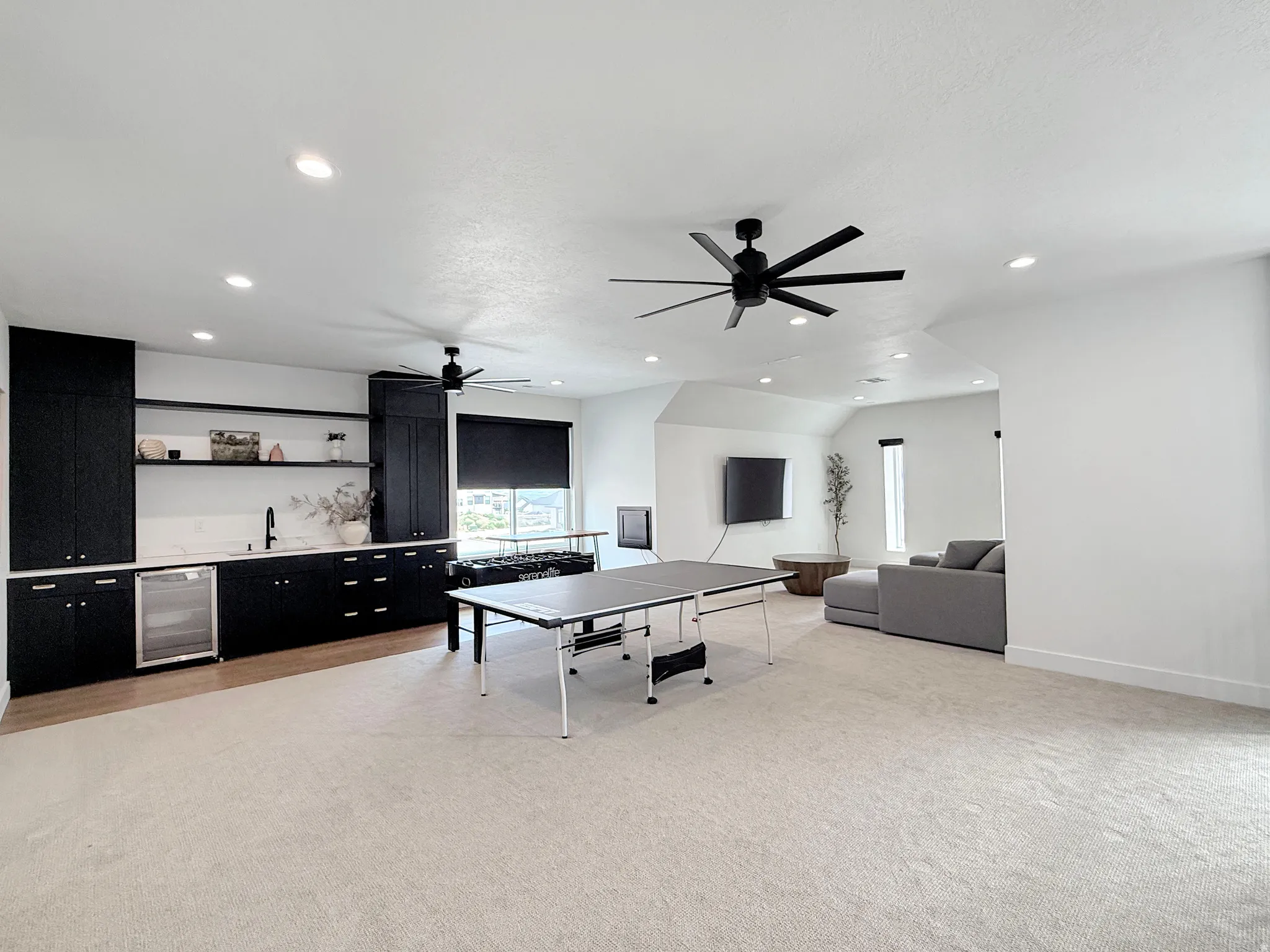 Integrated wet bar with black cabinetry, open shelving, and beverage cooler