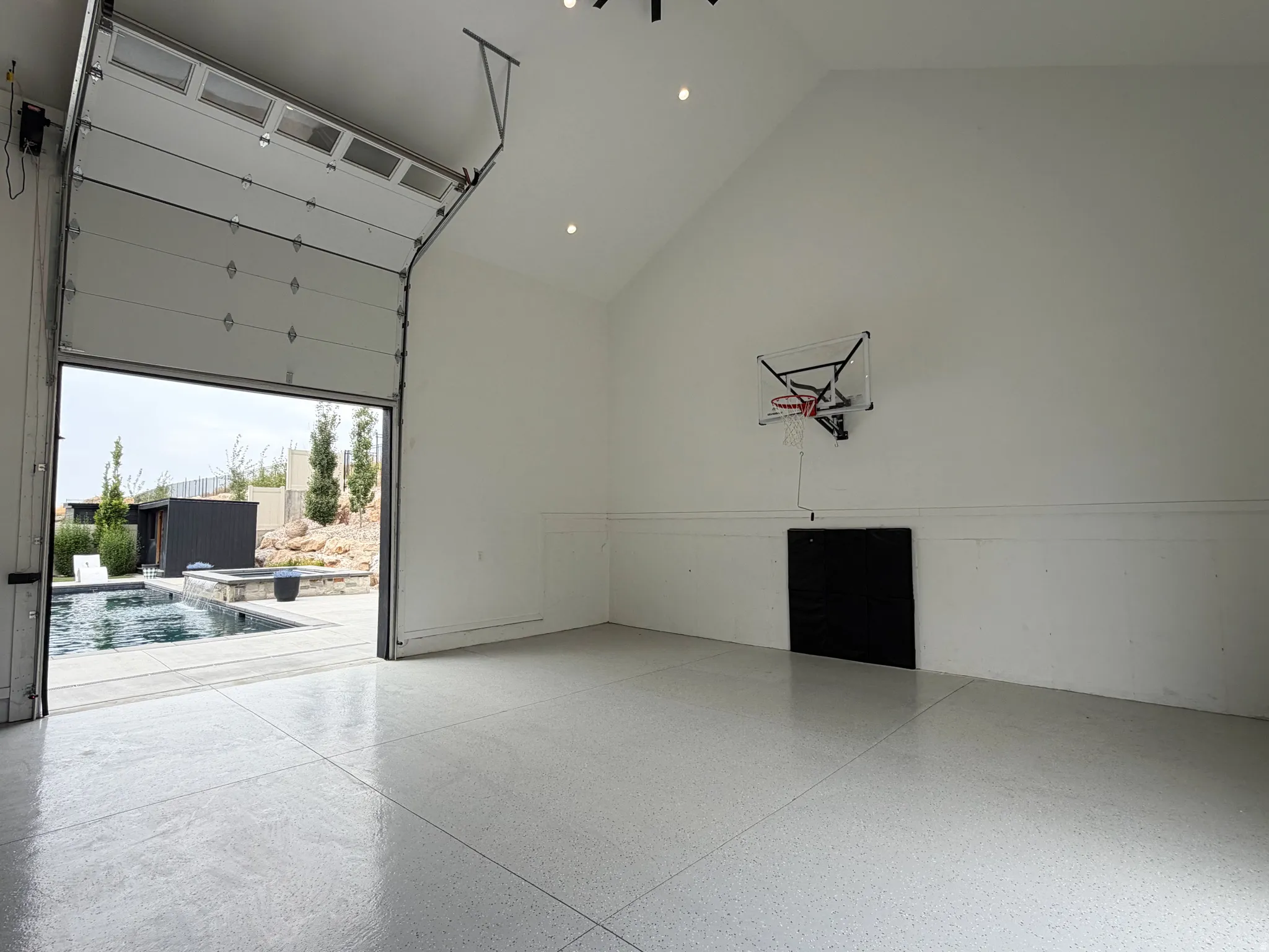 High vaulted ceiling, recessed lighting, polished concrete flooring, full-light garage door, and direct access to an outdoor pool