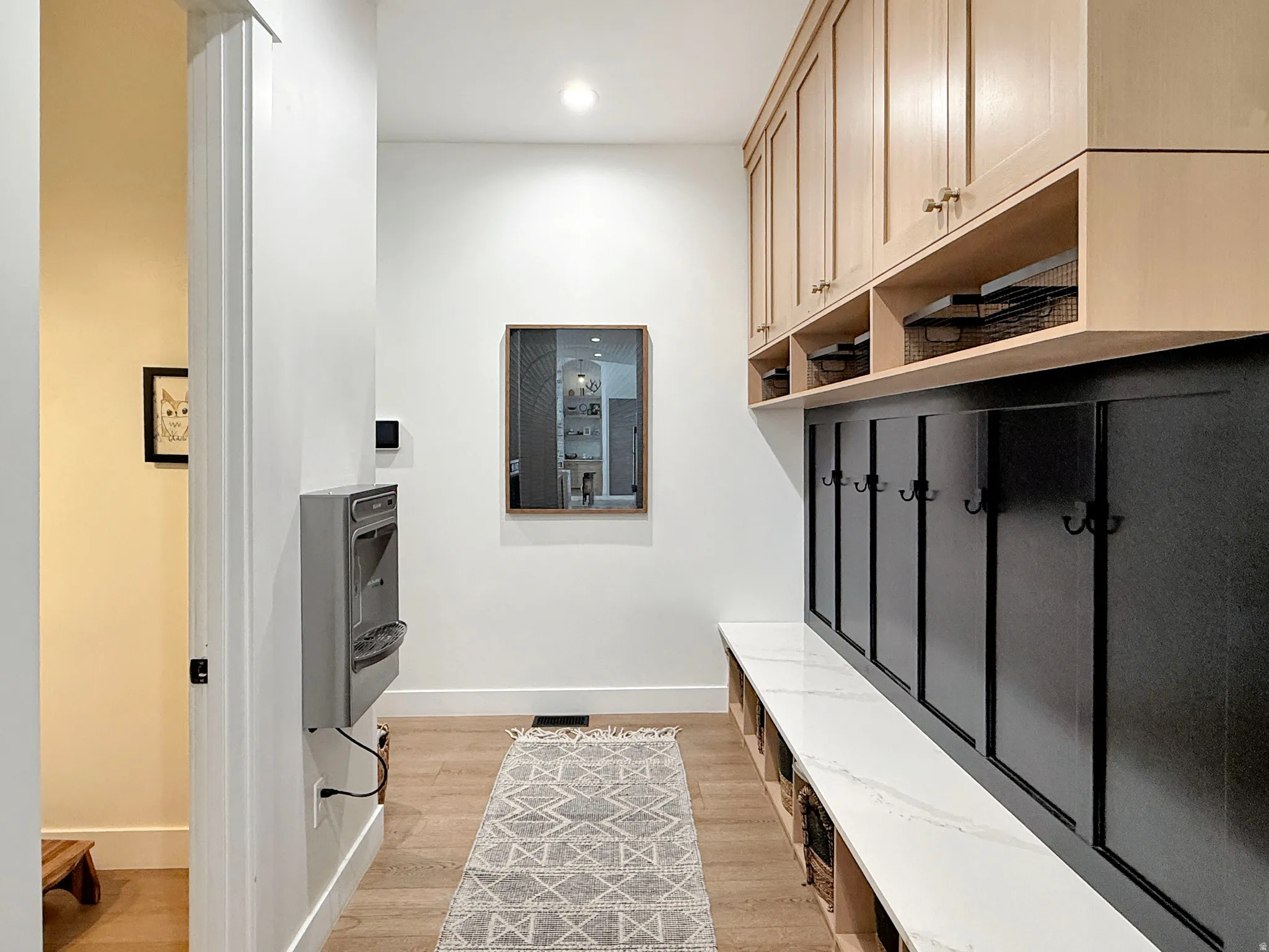 Custom built-in cabinetry with natural wood-finish doors and black paneling, integrated storage cubbies, and a white countertop
