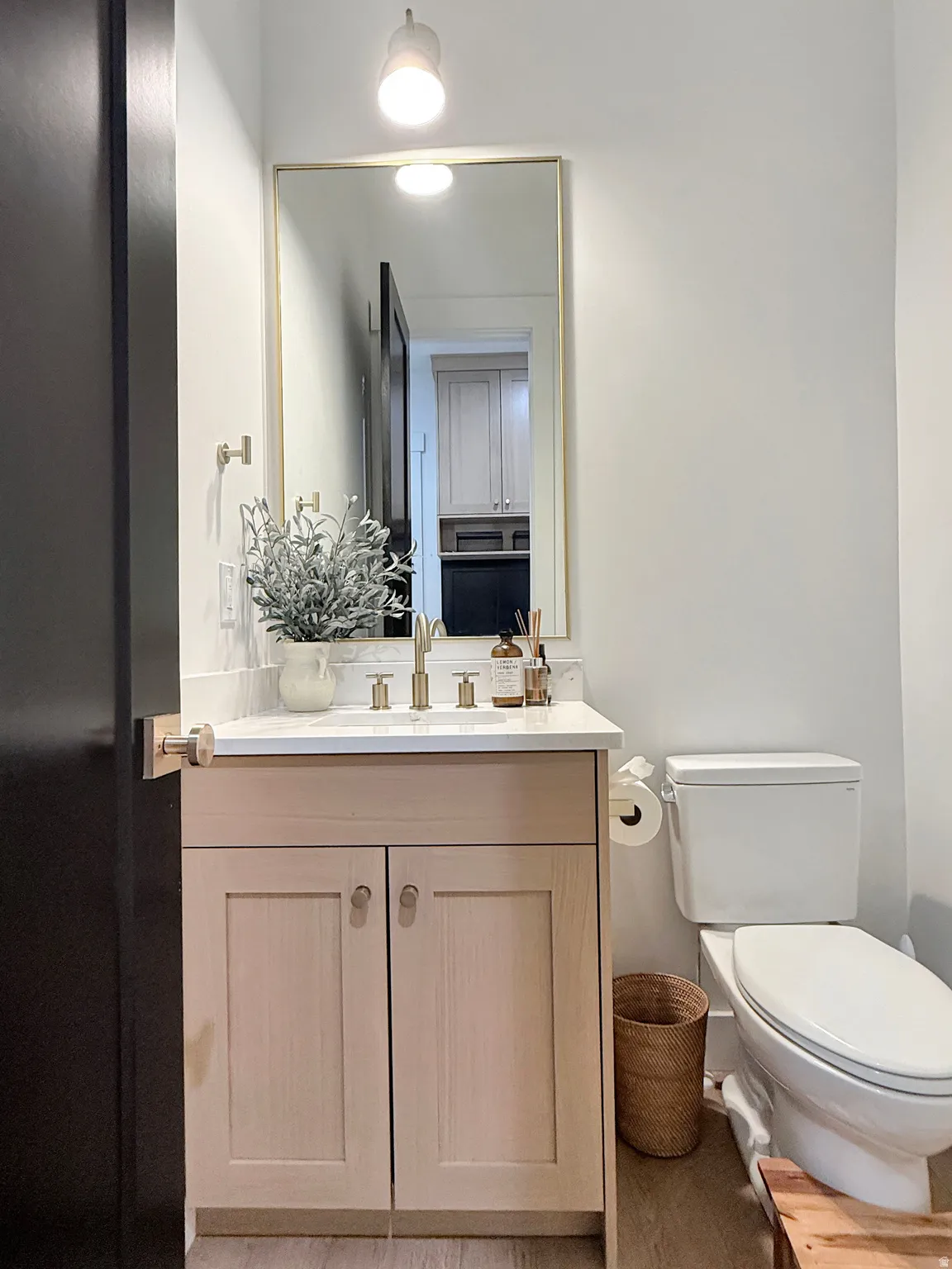 Light-toned wood-finish vanity with a white countertop and rectangular sink