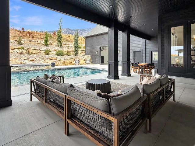 Covered outdoor patio with dark-stained wood ceiling and recessed lighting, leading to a concrete pool deck