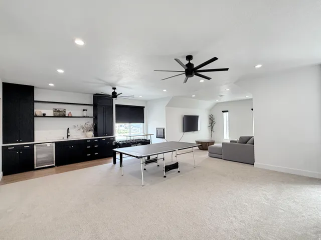 Integrated wet bar with black cabinetry, open shelving, and beverage cooler