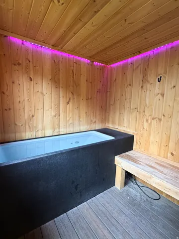Wood-paneled walls and ceiling, built-in soaking tub, built-in wooden bench, and composite wood flooring