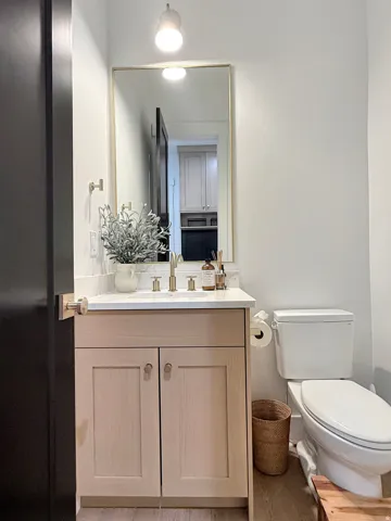Light-toned wood-finish vanity with a white countertop and rectangular sink