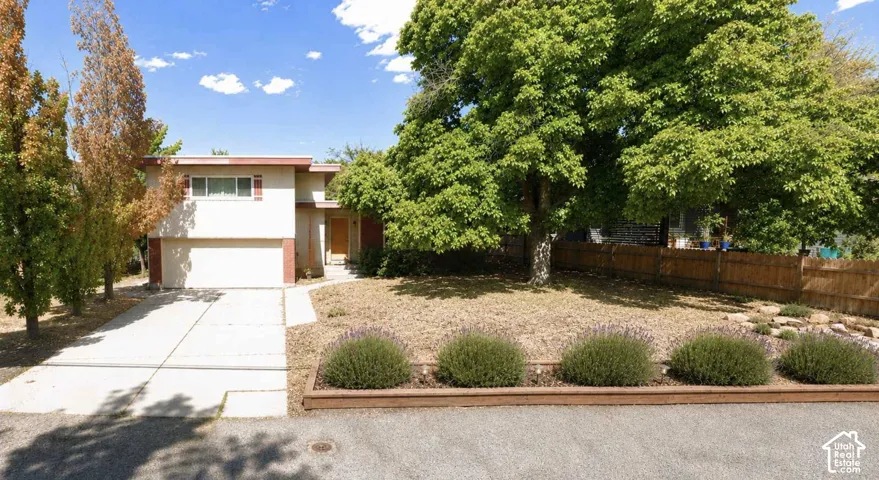 Two-story exterior with an attached garage, paved driveway, and mature landscaping