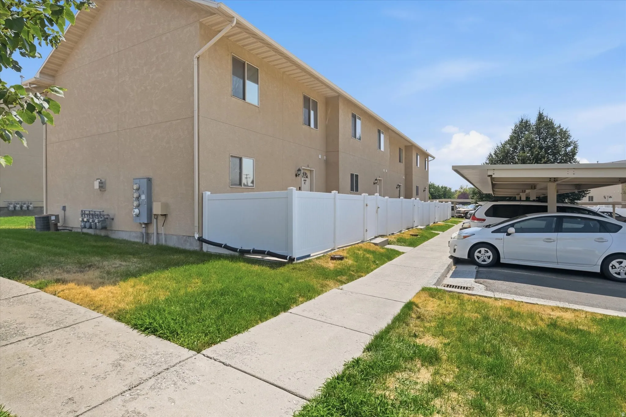 Stucco exterior featuring multiple windows and a white privacy fence