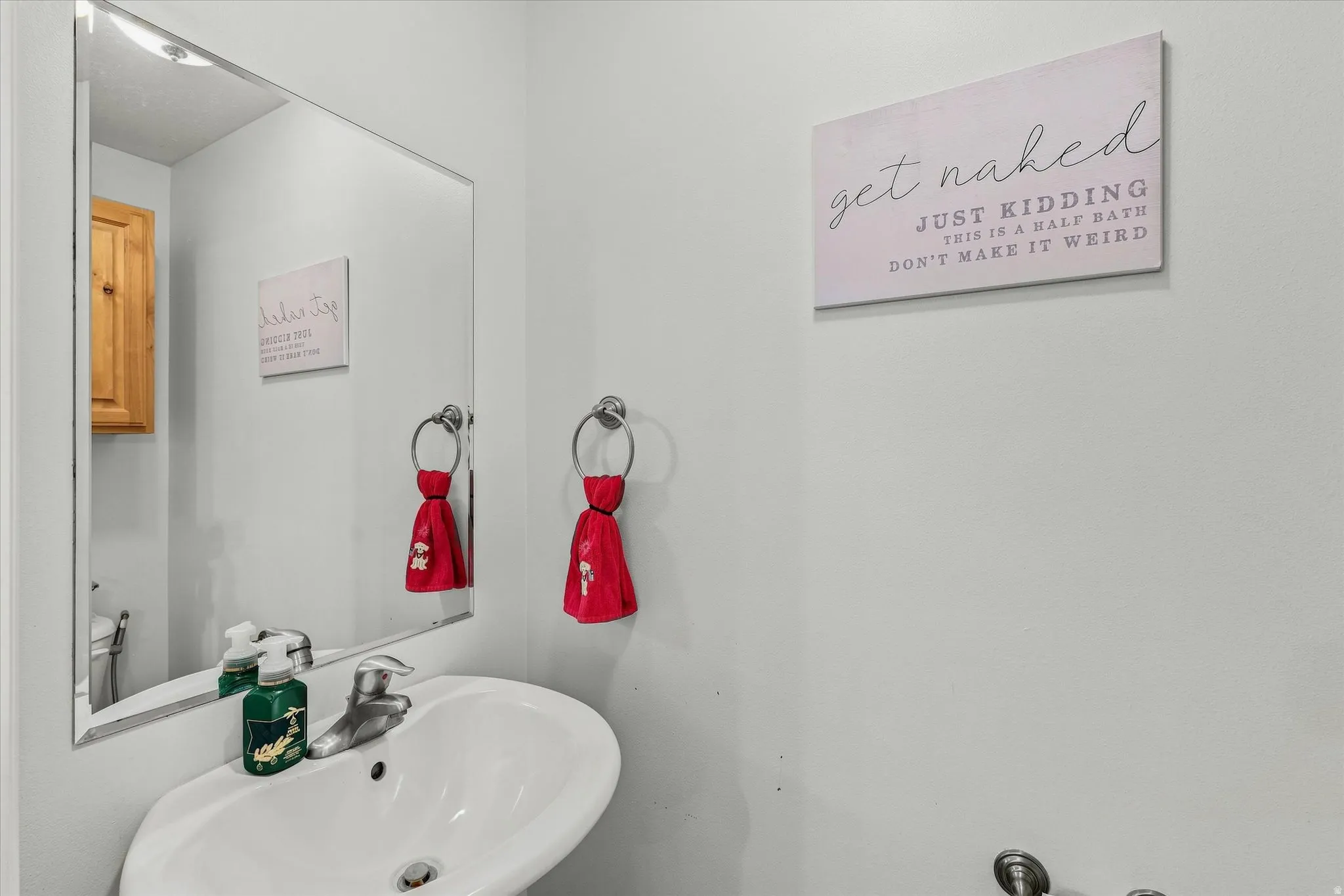 Wall-mounted sink with chrome faucet, large rectangular mirror, and light-toned wall paint