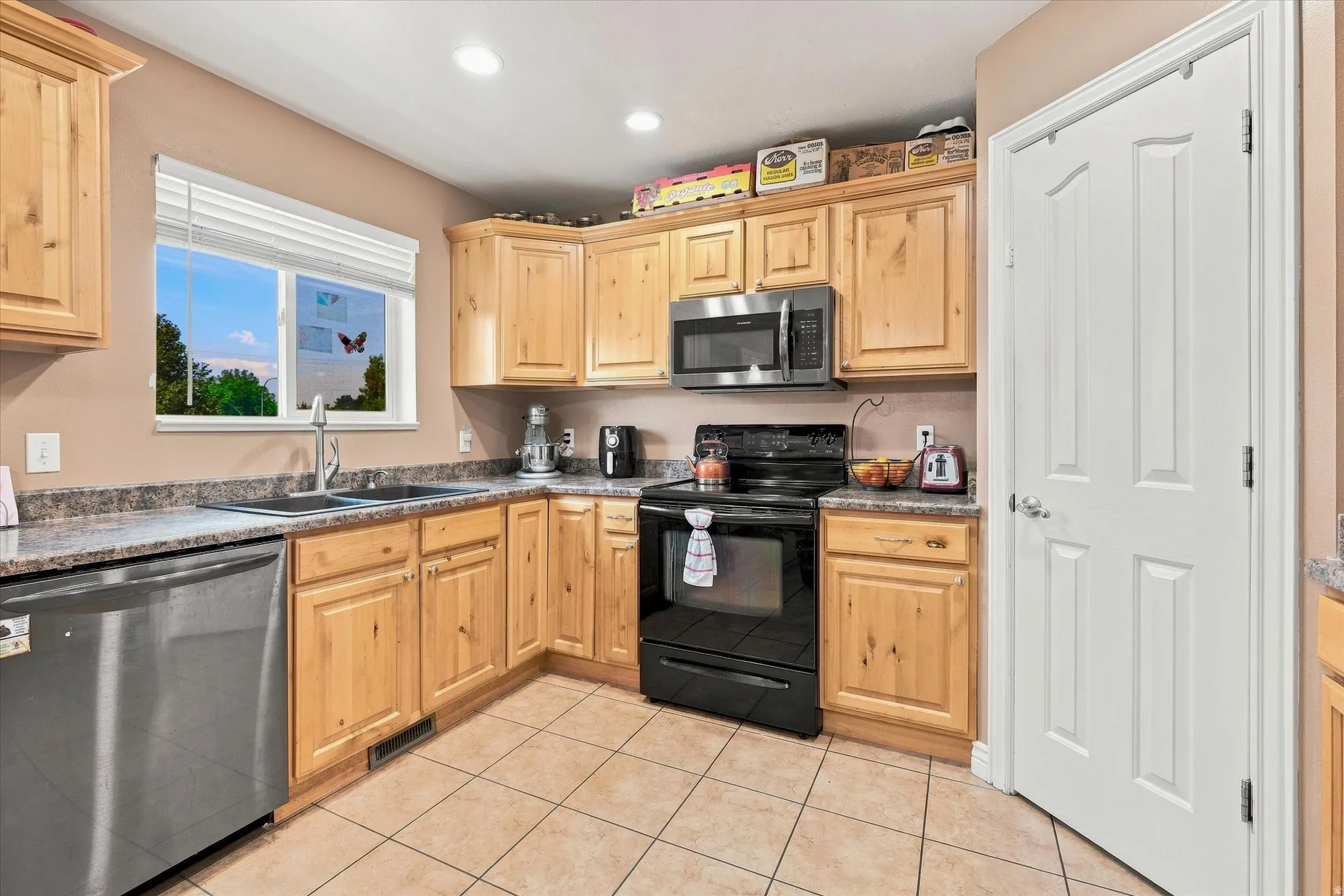 Full kitchen with wood cabinetry, stainless steel dishwasher, black oven, microwave, and laminate countertops