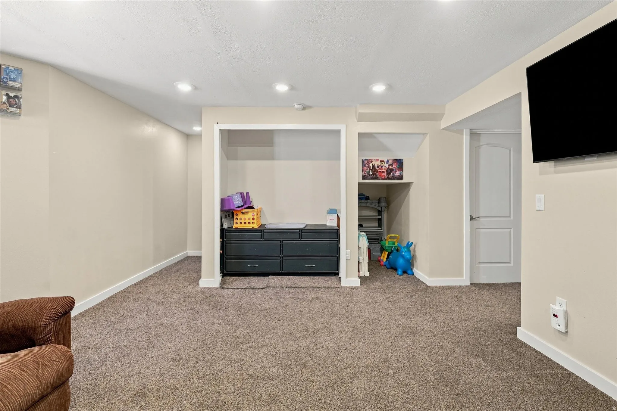 Recessed lighting illuminates the carpeted flooring