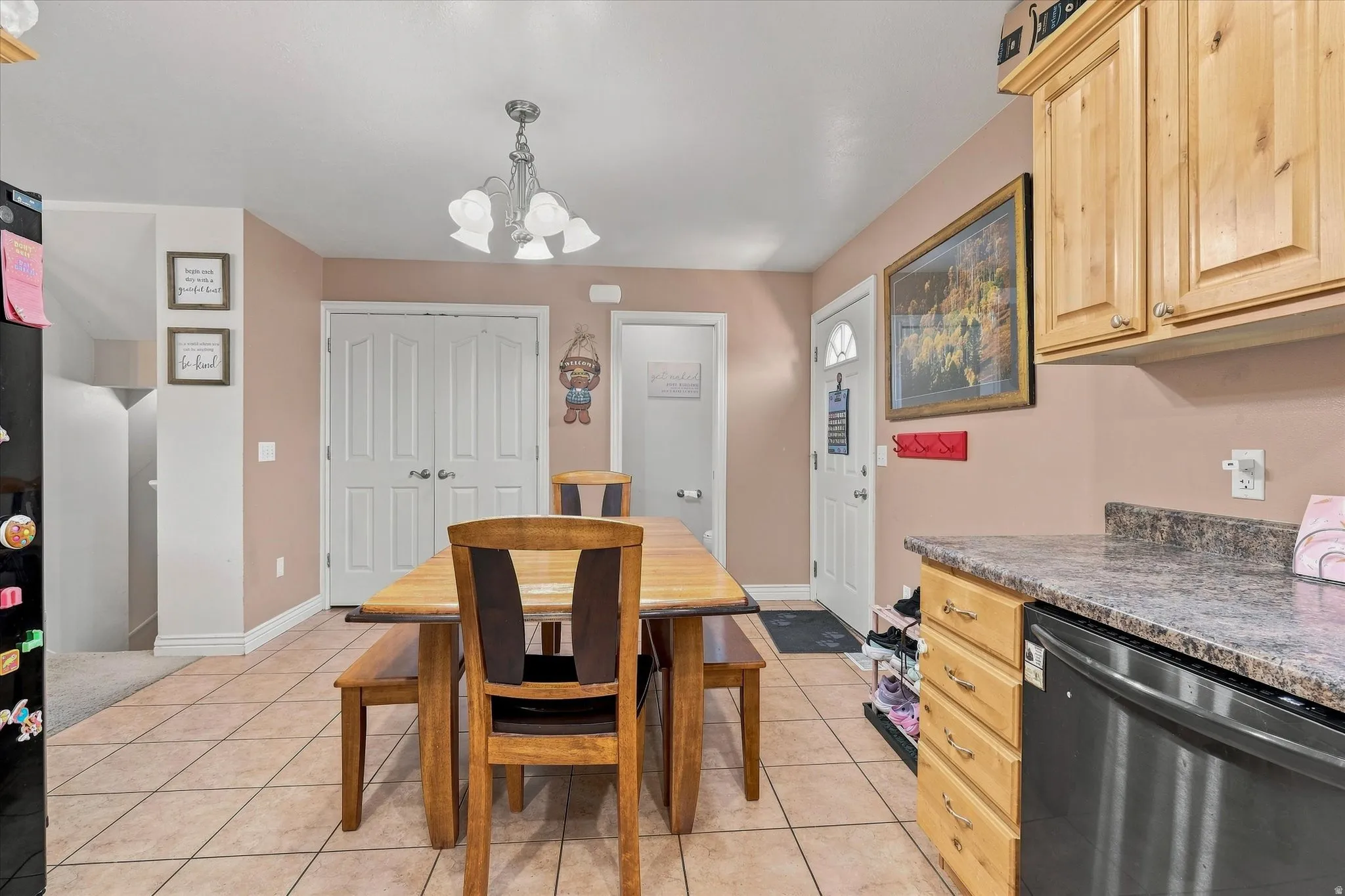 Tiled flooring, double-door pantry, wood-finish cabinetry, speckled countertop, and a white entry door