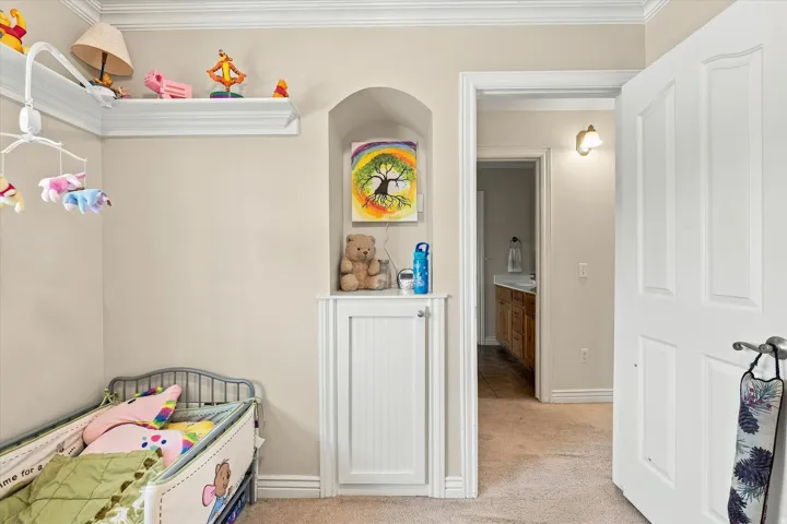 Built-in wall niche with beadboard cabinetry, crown molding, and an interior doorway leading to a bathroom with a wood-finish vanity