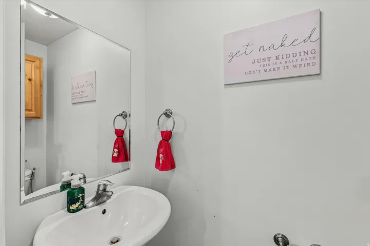 Wall-mounted sink with chrome faucet, large rectangular mirror, and light-toned wall paint