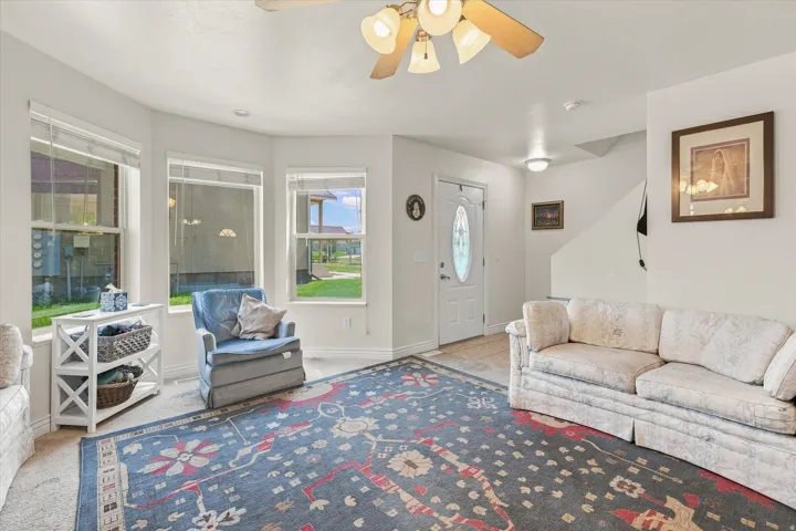 Bright living area featuring a bay window, ceiling fan, and staircase access