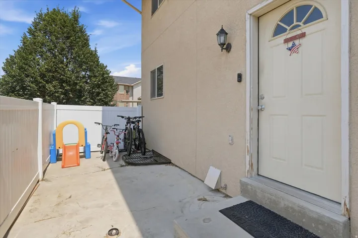 Exterior entry with a paneled door featuring an arched transom window, a wall-mounted light fixture, and a concrete pathway