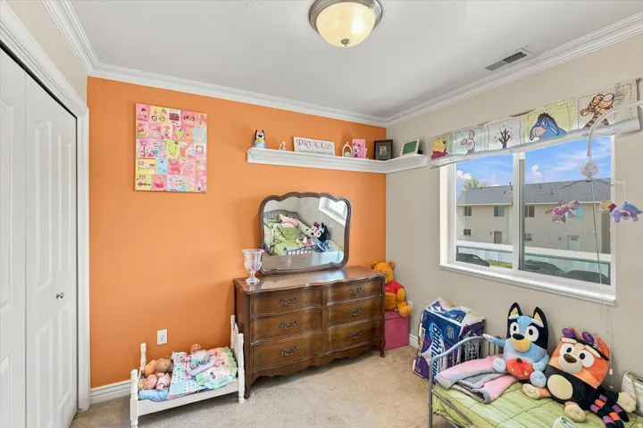 White bi-fold closet door, crown molding, built-in corner shelf, window with white trim, and a semi-flush mount ceiling light fixture