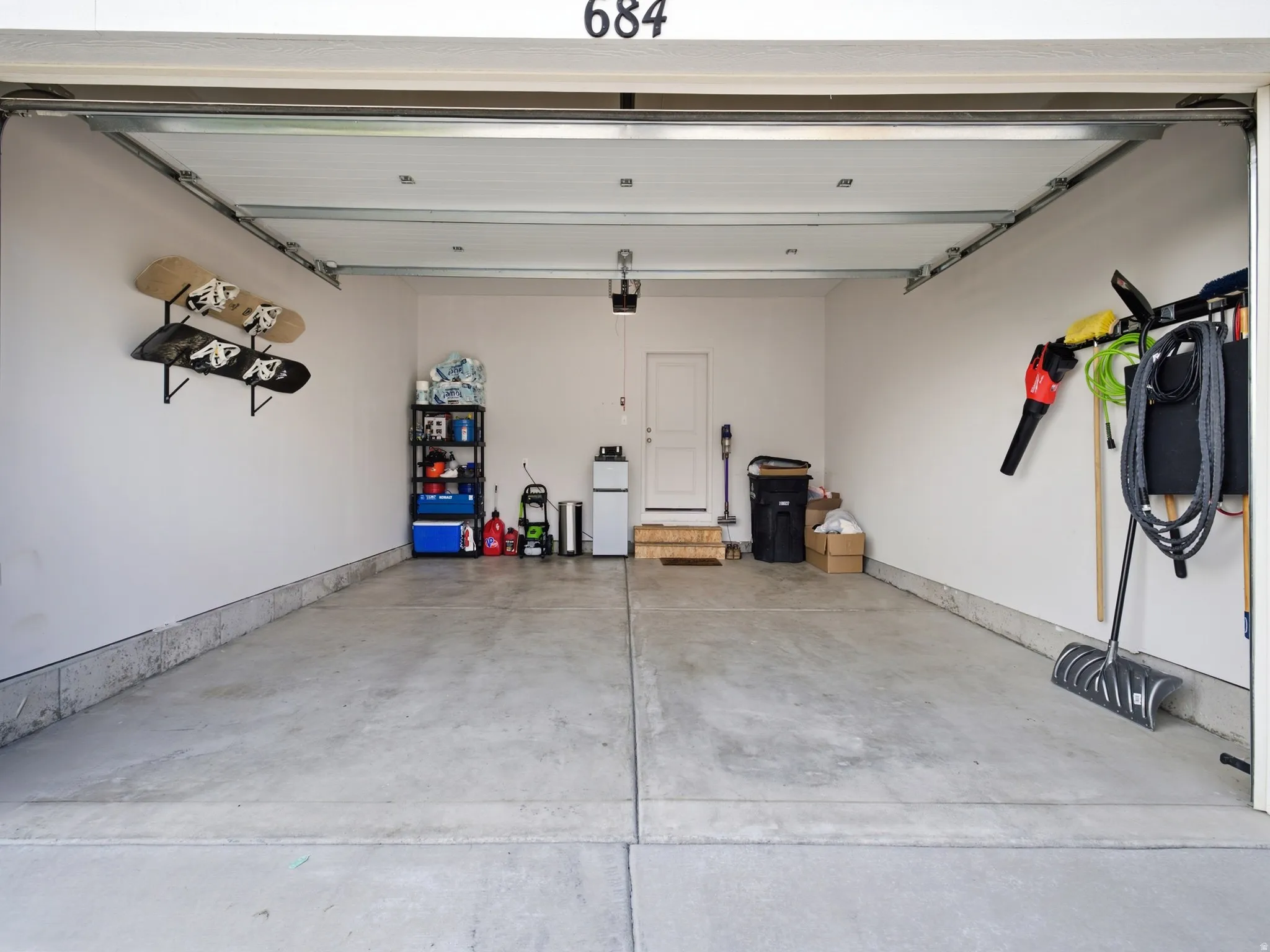 Spacious garage featuring a concrete floor, overhead garage door, and interior access door