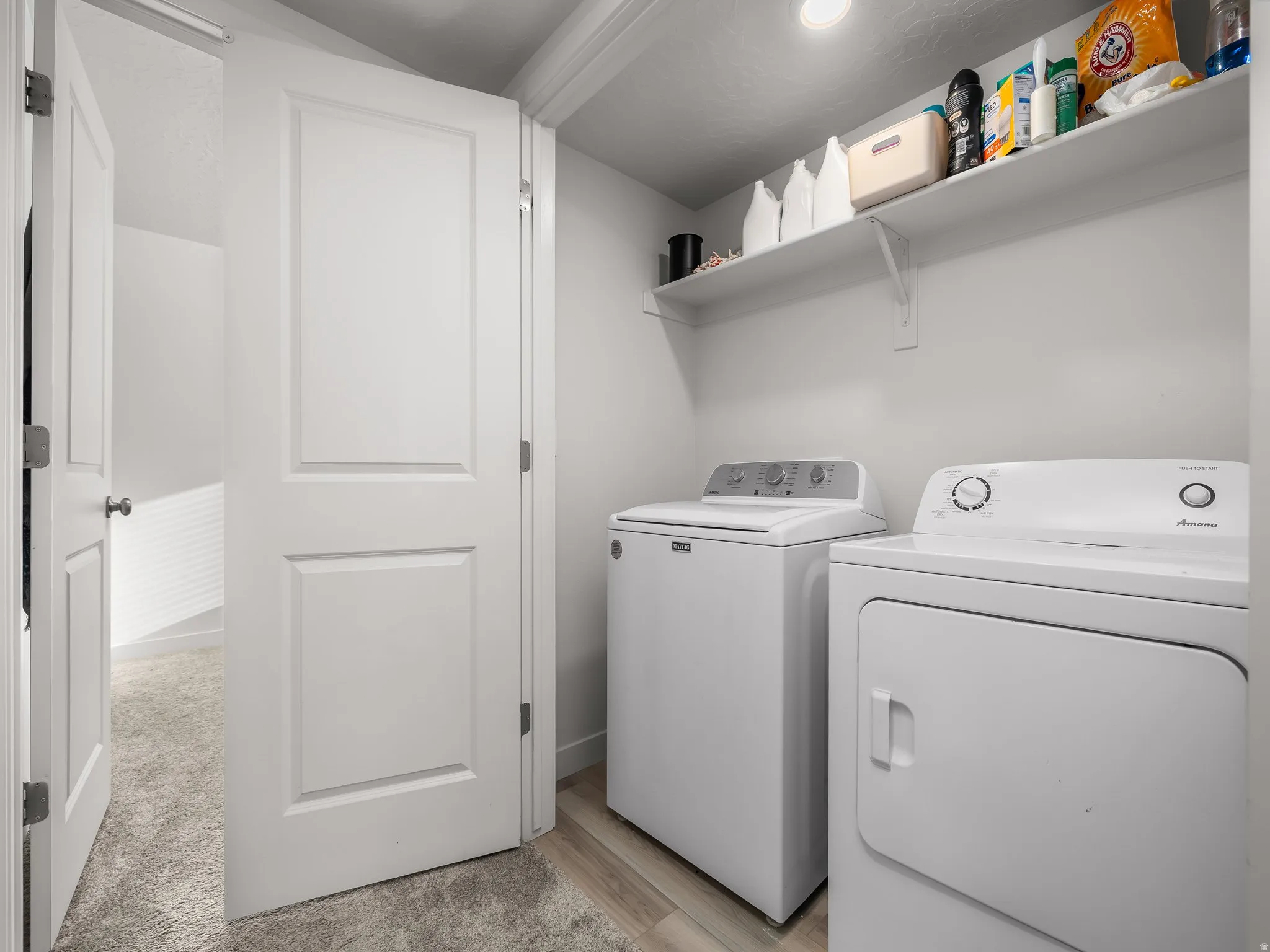 Dedicated laundry area featuring a built-in shelf and wood-finish flooring