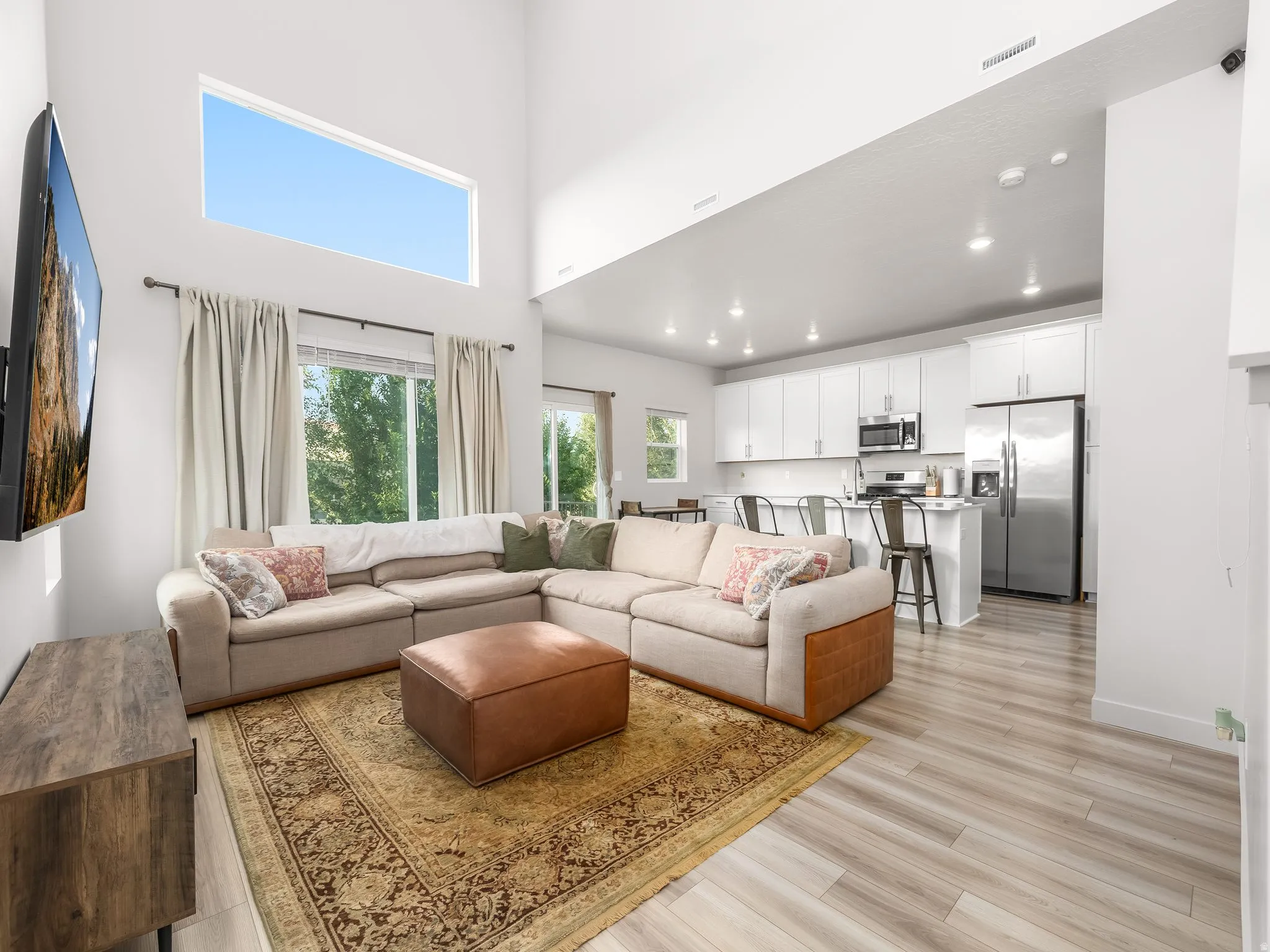 Open concept living area with vaulted ceilings, a high-level transom window, and wood-finish flooring