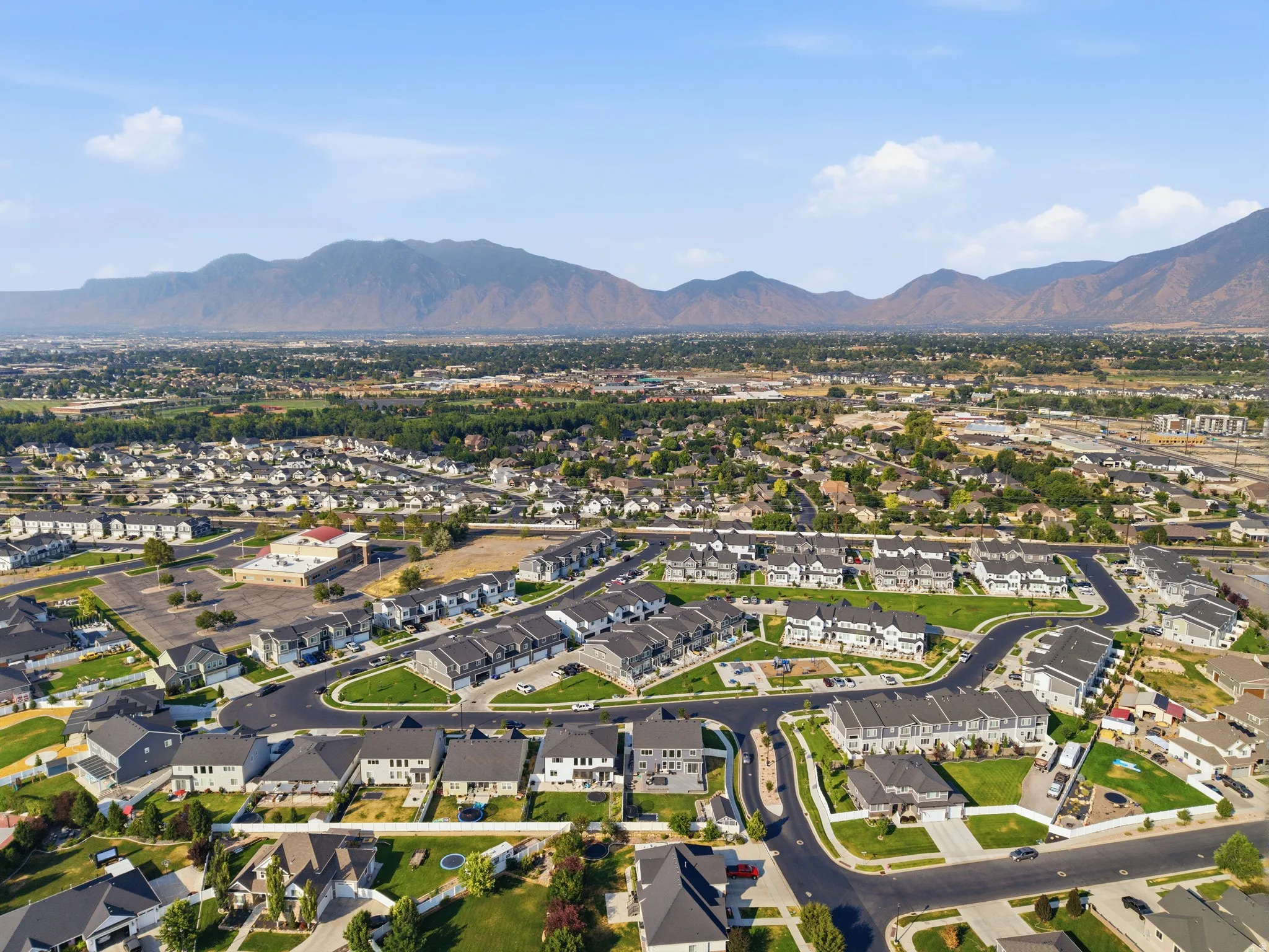 Aerial view showcasing a planned residential community with curved street layouts, manicured landscaping, and new construction homes