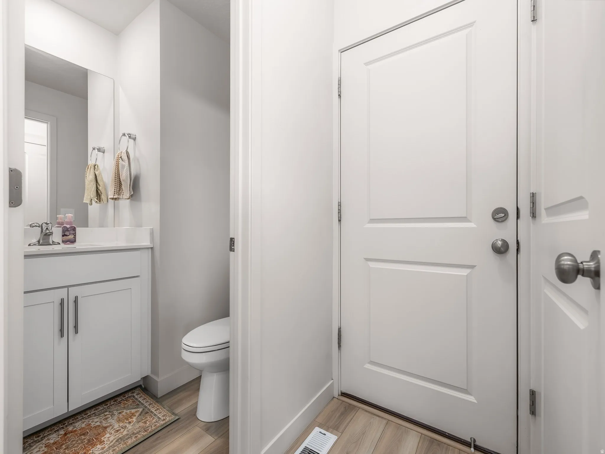 White vanity with cabinet storage, countertop, and a wall-mounted mirror