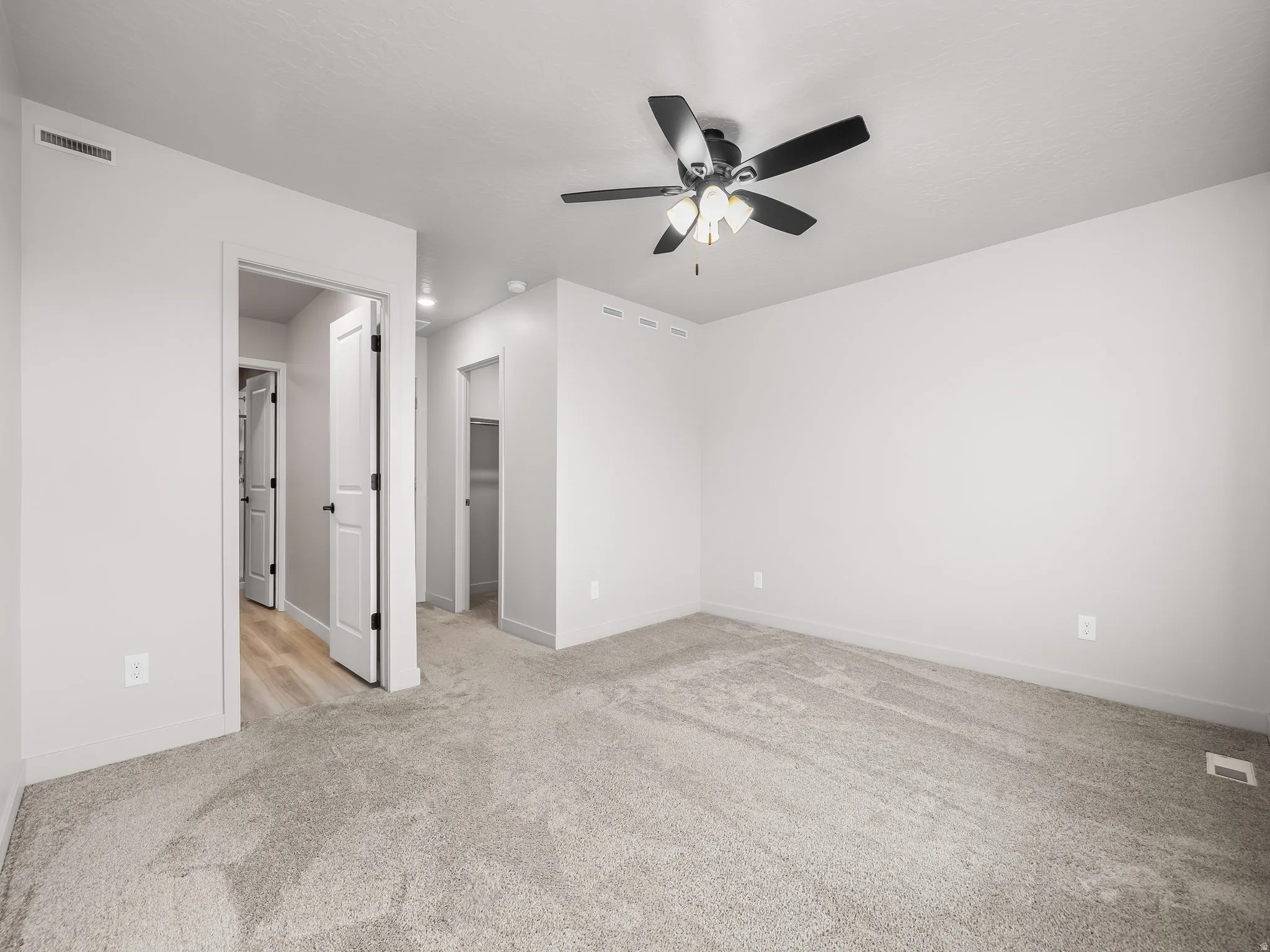 Neutral wall paint, ceiling fan with integrated lighting, and plush carpet flooring