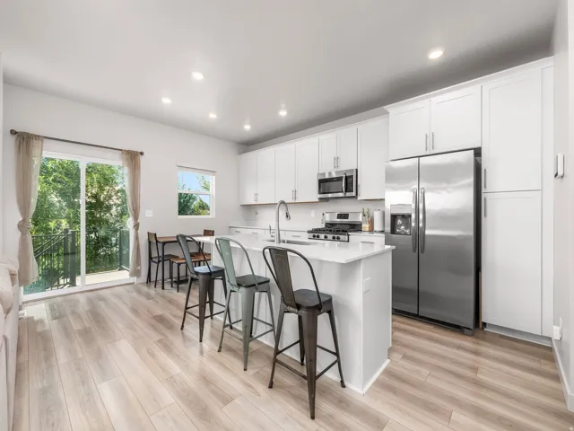 Well-appointed kitchen featuring white cabinetry, stainless steel appliances, a center island with countertop seating, and light wood-finish flooring