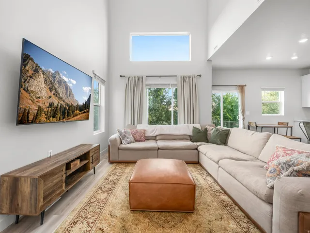 Vaulted ceilings with clerestory windows, wood-finish flooring, and sliding glass doors