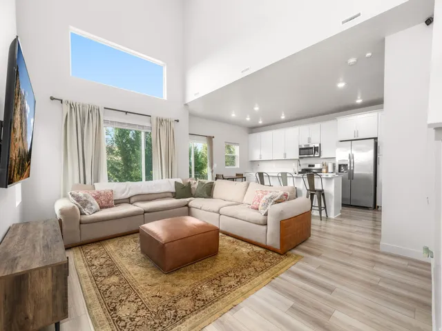 Open concept living area with vaulted ceilings, a high-level transom window, and wood-finish flooring