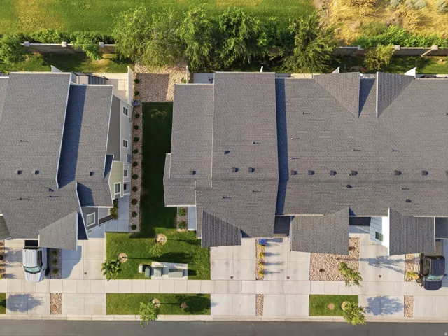 Aerial perspective showcasing multiple properties with dark shingle roofs, landscaped front yards, and paved driveways