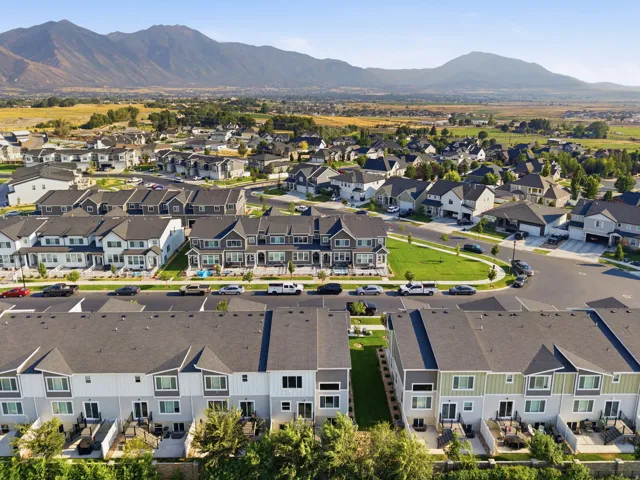 Residential community featuring modern townhomes and detached residences, surrounded by green spaces and distant mountains