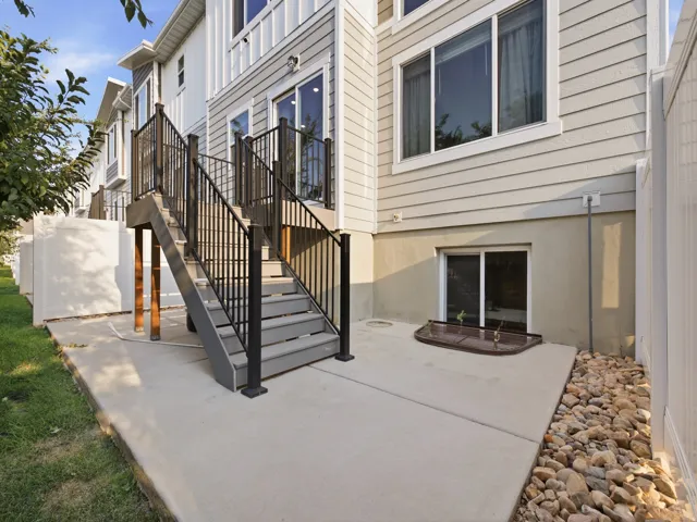 Concrete patio with an exterior staircase featuring black metal railings