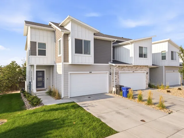 Modern multi-story exterior with vertical and horizontal siding, stone accents, attached garage, and a covered entry