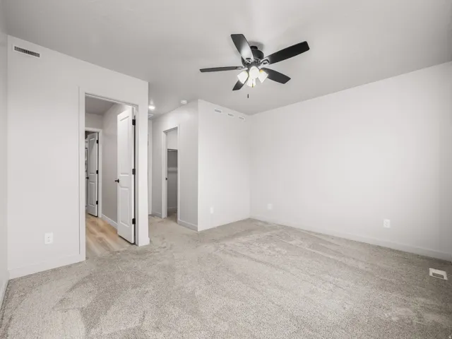 Neutral wall paint, ceiling fan with integrated lighting, and plush carpet flooring