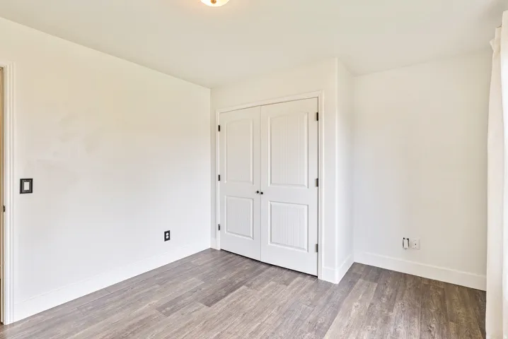 Wood-finish flooring with white baseboards and neutral wall paint