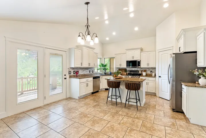 Kitchen featuring an island, white cabinetry, integrated stainless steel appliances, and a tile backsplash