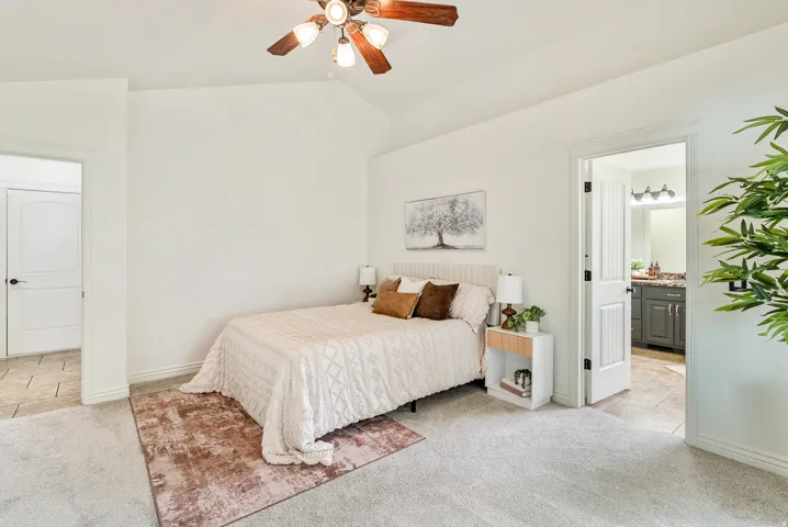 Vaulted ceiling with a ceiling fan, plush carpet flooring, panel doors, and tile flooring