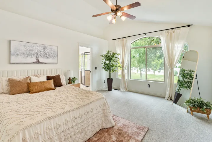 Vaulted ceiling with a ceiling fan, arched window, and light-colored carpeting