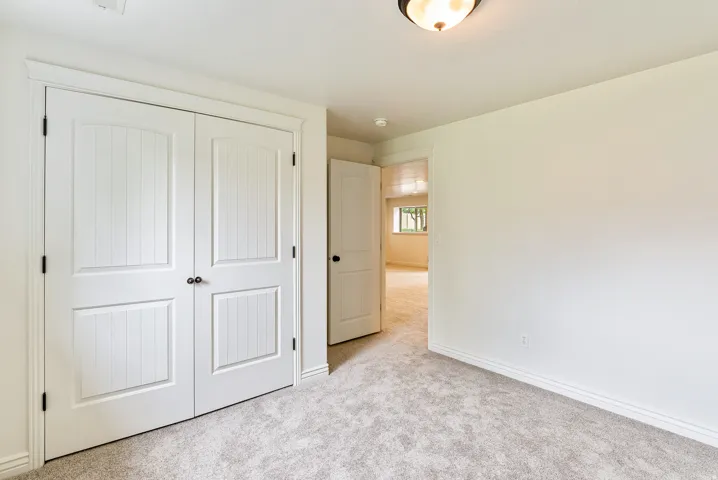 White paneled double doors with dark hardware, light gray carpeting, and a flush mount ceiling light fixture