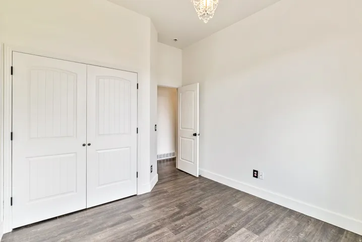 Wood-finish flooring, white walls, and a crystal chandelier