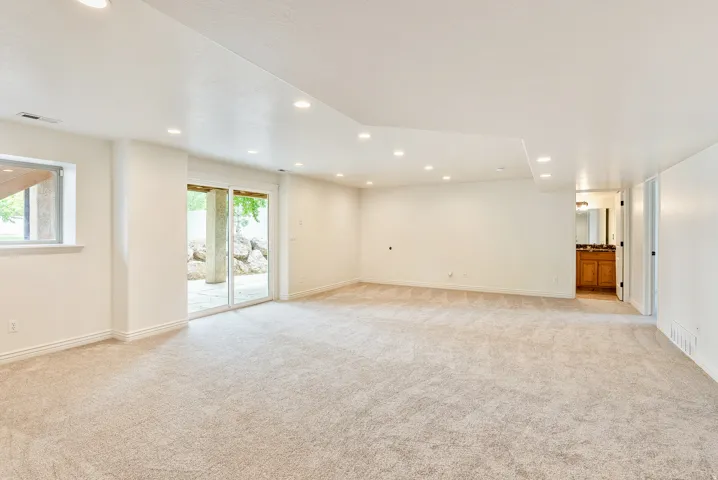Expansive room with neutral carpeting, recessed lighting, and sliding glass doors to exterior