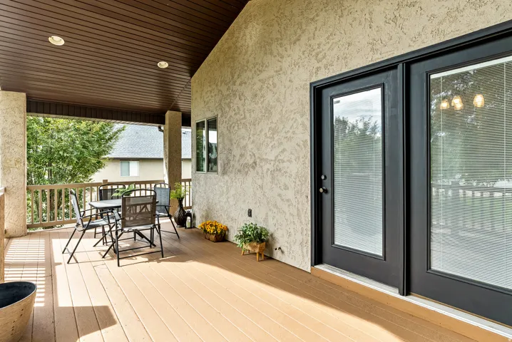 Spacious covered deck featuring a textured stucco exterior, wood-finish flooring, recessed lighting, and dual exterior glass-panel doors