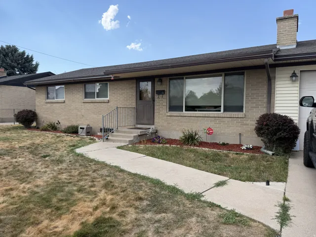 Brick exterior with dark brown trim and a concrete pathway leading to the front entry
